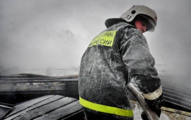 Barnaul, Rusya. 24 Aralık 2019. İtfaiyeciler soğuk bir kış gününde evin çatısındaki yangını söndürürler.