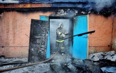 Barnaul, Rusya. 24 Aralık 2019. İtfaiyeciler soğuk bir kış gününde evin çatısındaki yangını söndürürler.