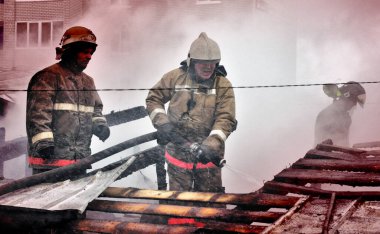 Barnaul, Rusya. 24 Aralık 2019. İtfaiyeciler soğuk bir kış gününde evin çatısındaki yangını söndürürler.