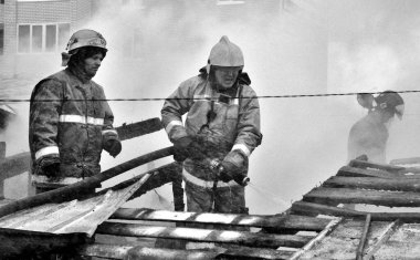 Barnaul, Rusya. 24 Aralık 2019. İtfaiyeciler soğuk bir kış gününde evin çatısındaki yangını söndürürler.