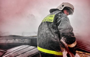 Barnaul, Rusya. 24 Aralık 2019. İtfaiyeciler soğuk bir kış gününde evin çatısındaki yangını söndürürler.