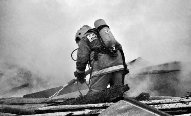 İtfaiyeciler soğuk bir kış gününde evin çatısındaki yangını söndürürler.