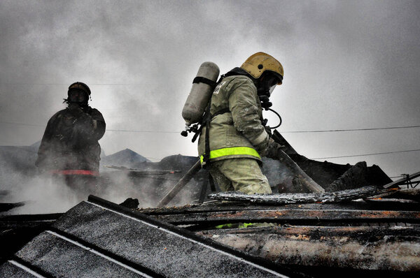 Firefighters with the inscription on the back in Russian "Fire protection" extinguish the fire on the fire