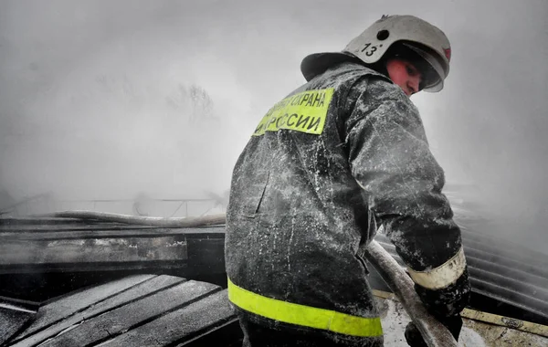 ロシアのバルナウル 2019年12月24日 寒い冬の日に家の屋根に火を消す消防士 — ストック写真