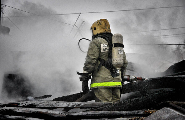 Firefighters with the inscription on the back in Russian "Fire protection" extinguish the fire on the fire