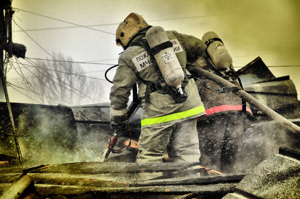 Firefighters with the inscription on the back in Russian "Fire protection" extinguish the fire on the fire