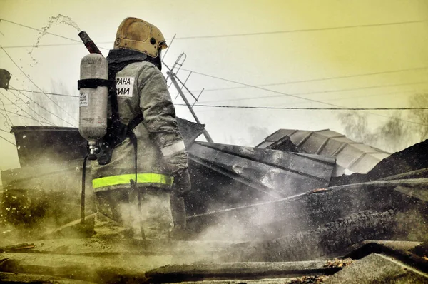 ロシア語で背中に碑文を持つ消防士 火災で火災を消火 — ストック写真