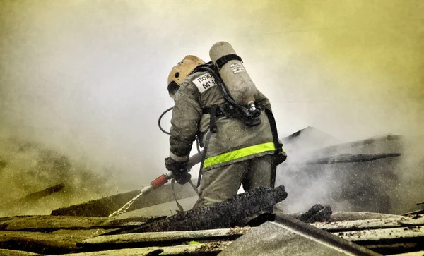 ロシア語で背中に碑文を持つ消防士 火災で火災を消火 — ストック写真