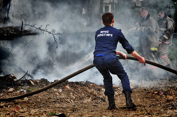 Barnaul, Russia - May 24, 2019. Firefighters with the inscription on the back in Russian "Fire protection" extinguish the fire on the fire