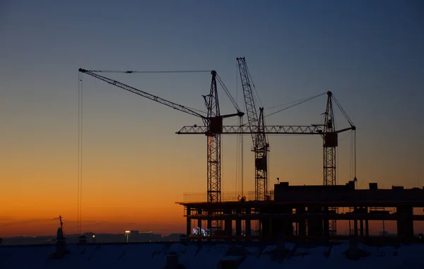 Guindastes Construção Estão Construindo Uma Casa Contra Fundo Pôr Sol — Fotografia de Stock