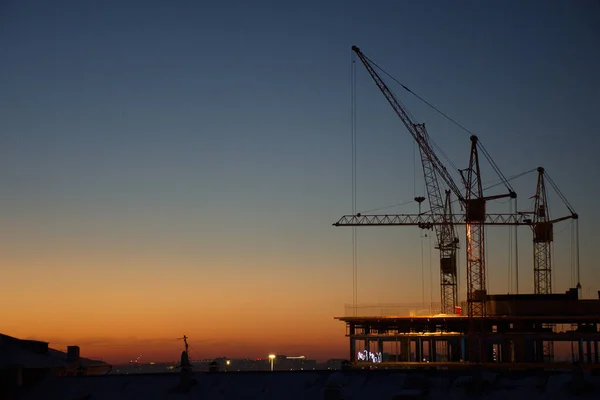 Guindastes Construção Estão Construindo Uma Casa Contra Fundo Pôr Sol — Fotografia de Stock