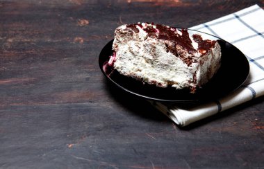 Tabakta bir dilim lezzetli çikolatalı pasta var. Ahşap arka planda lezzetli bir tatlı, yakın planda.