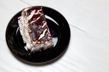 Tabakta bir dilim lezzetli çikolatalı pasta var. Ahşap arka planda lezzetli bir tatlı, yakın planda.