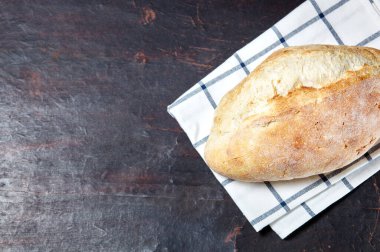 Ahşap bir arka planda ekmek. Koyu mutfak masasında taze fırın.