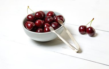 Ahşap arka planda seramik bir kasede tatlı kirazlar, yakın plan. Taze taze kirazlar bir kase içinde su damlacıkları