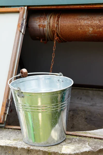 Metal bucket at draw-well in European village. Retro stone water well in rural area