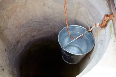 Avrupa köyünde metal bir kova var. Kırsal bölgedeki Retro Stone Kuyusu