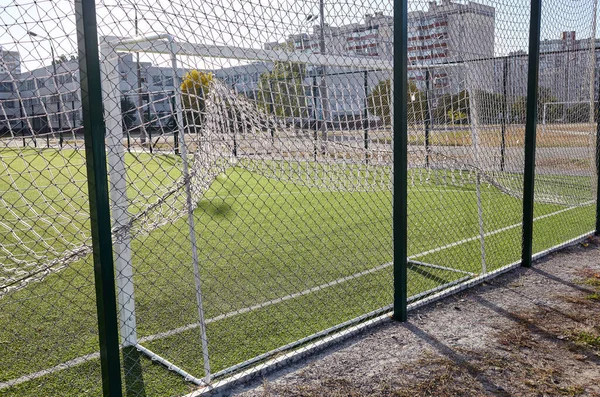 芝生のフィールドは 緑のフェンスメッシュの後ろにサッカーをプレイする 緑の芝生のサッカー場の閉鎖 — ストック写真