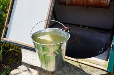 Avrupa köyünde metal bir kova var. Kırsal bölgedeki Retro Stone Kuyusu