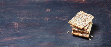 Tohumlu çıtır ekmek. Tahta zeminde çıtır çıtır çıtır çıtır ekmek. Sağlıklı atıştırmalık: mısır gevreği, çoklu tahıllı keten tohumu, ayçiçeği tohumlu protein çubuğu.