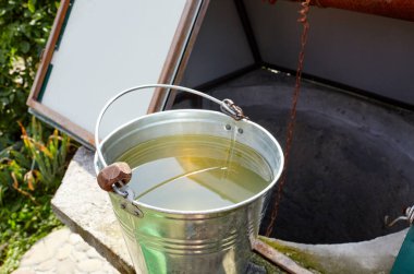 Avrupa köyünde metal bir kova var. Kırsal bölgedeki Retro Stone Kuyusu