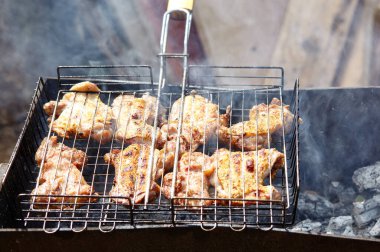 Izgarada pişen leziz tavuk kanatları, açık havada. Kızarmış tavuk eti, yakın plan.