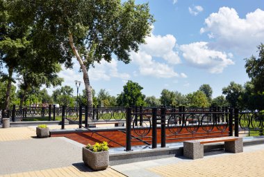 Çiçekler ve süslü çalılarla çevrili banka ve merdivenlere sahip dinlenme alanı. Şehir parkında dinlenecek bir yer.