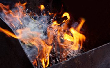 Burning red hot sparks fly from fire. Barbecue gril with glowing and flaming hot charcoal and firewood