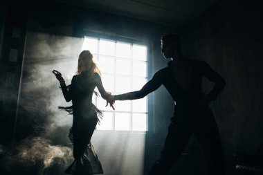İki profesyonel balo dansçısı çatı katında dans ediyor. Ağır dumanla güzel bir sanat gösterisi. Spor hayatı konsepti. Tutku ve duygusal dans.