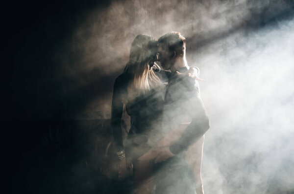 Couple of two professional ballroom dancers is dancing on loft studio. Beautiful art performance with heavy smoke. Sport life concept. Passion and emotional dance.