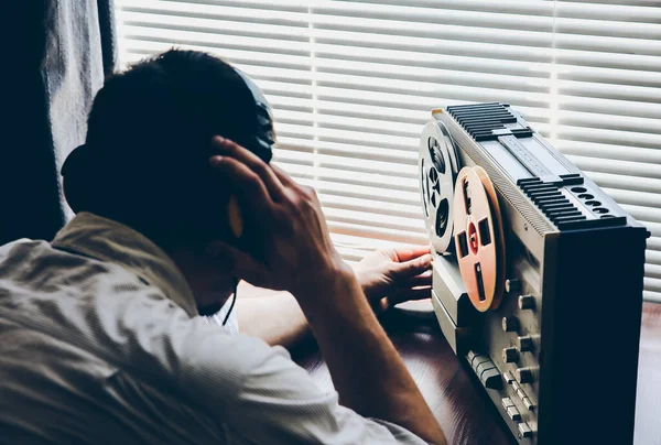 Special agent listens on the reel tape recorder. Officer wiretapping in headphones. KGB spying of conversations.