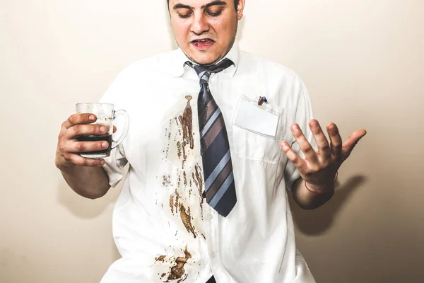 Office worker spills coffee on white shirt. Occupational burnout. Unhappy manager with mug in hands. Stressful job. Desperate man.