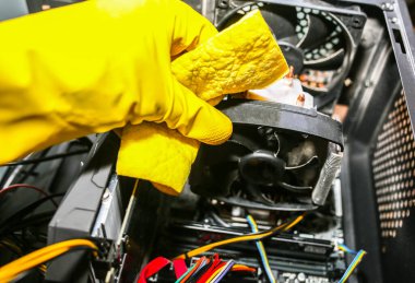 Inside details of the personal computer. Man is cleaning wires in yellow gloves. Motherboard and video card in the dust. Broken PC.