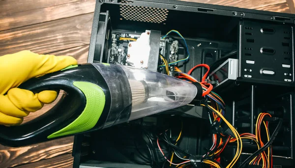 Kişisel bilgisayarın içinde. Adam elektrik süpürgesiyle kablo temizliyor. Küçük süpürge. Anakart ve video kartı toz içinde. Kırık PC.