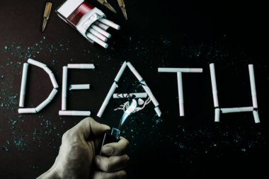 Sigaradan ölüm işareti. Dumandan kurukafa. Tehlikeli bir alışkanlık. Sağlığa zararlı. Adamın elinde çakmak var..