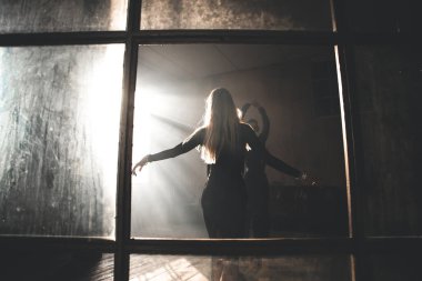 İki profesyonel balo dansçısı çatı katında dans ediyor. Ağır dumanla güzel bir sanat gösterisi. Spor hayatı konsepti. Tutku ve duygusal dans.