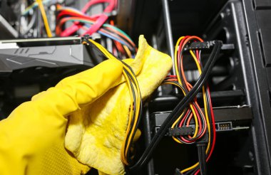 Inside details of the personal computer. Man is cleaning wires in yellow gloves. Motherboard and video card in the dust. Broken PC.