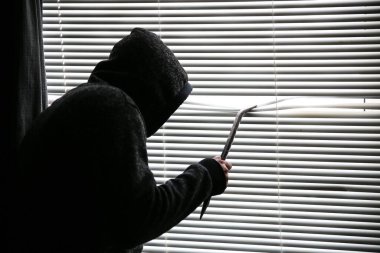 Levyeli bir suçlu pencereden gözetliyor. Eski panjurlar.