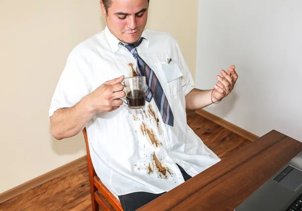 Office worker spills coffee on white shirt. Occupational burnout. Unhappy manager with mug in hands. Stressful job at the desk. Desperate man.