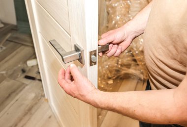 Adam kapı kolunu kuruyor. Onarım işe yarıyor. Dairede bakım var..