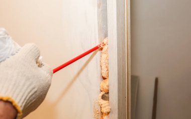 Adam sprey köpükle kapıyı kuruyor. Onarım işe yarıyor. Dairede bakım var..