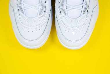 Sarı arka planda modern spor ayakkabılar. Çivili büyük tabanlı beyaz deri ayakkabılar. Kapat..