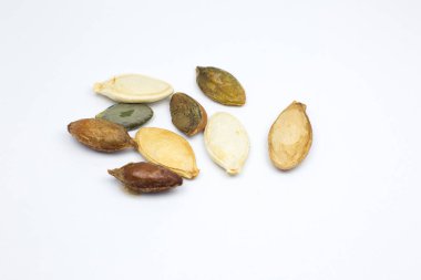 Beyaz arka planda farklı renklerde kavrulmuş balkabağı tohumları. Lezzetli ve sağlıklı yiyecekler. Fotoğrafı kapat..