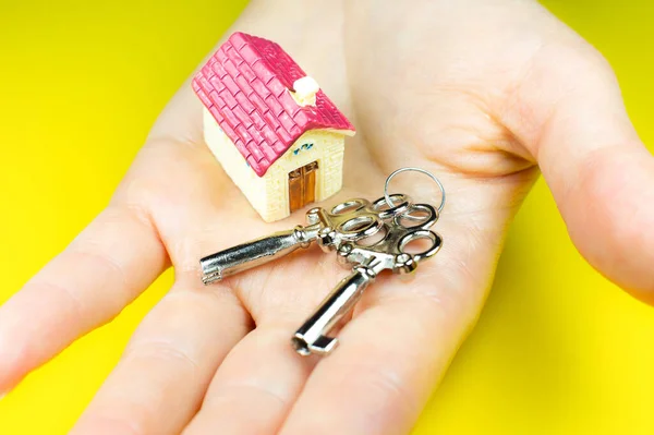 House and keys on woman hands. Buying and renting real estate. Bank credit for property. Save money.