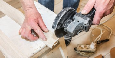 Adam süpürgelik kesiyor. İçeride tamirat işe yarar. Dairede tadilat var. Açı öğütücü ellerinde.