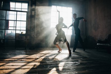 İki profesyonel balo dansçısı çatı katında dans ediyor. Ağır dumanla güzel bir sanat gösterisi. Spor hayatı konsepti. Tutku ve duygusal dans.