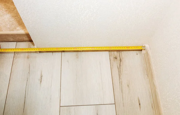 Baseboard installation. Repair works indoors. Renovation in the flat.  Tape measure.