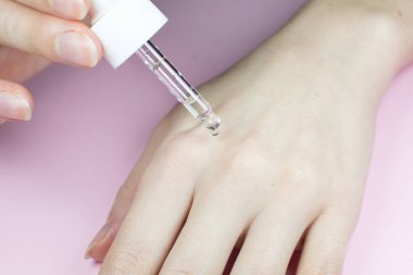 Pipetli bir şişe kozmetik yağı. Kadın derisine damlayan sıvı damlasını kapat. Güzellik, ilaç ve sağlık hizmetleri konsepti. Makro fotoğraf. Doğal, eko kozmetik.