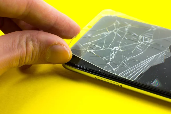 Man replacing the broken tempered glass screen protector. Crashed smartphone. Close up.