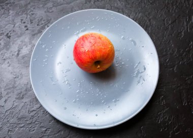 Gri tabakta duran bir elma. Durgun bir fotoğraf. Siyah arkaplan.